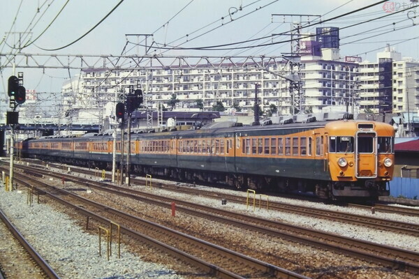 横浜駅付近を行く、湘南色の国鉄型153系電車による急行「東海・ごてんば」。1981年7月撮影（画像：PIXTA）。