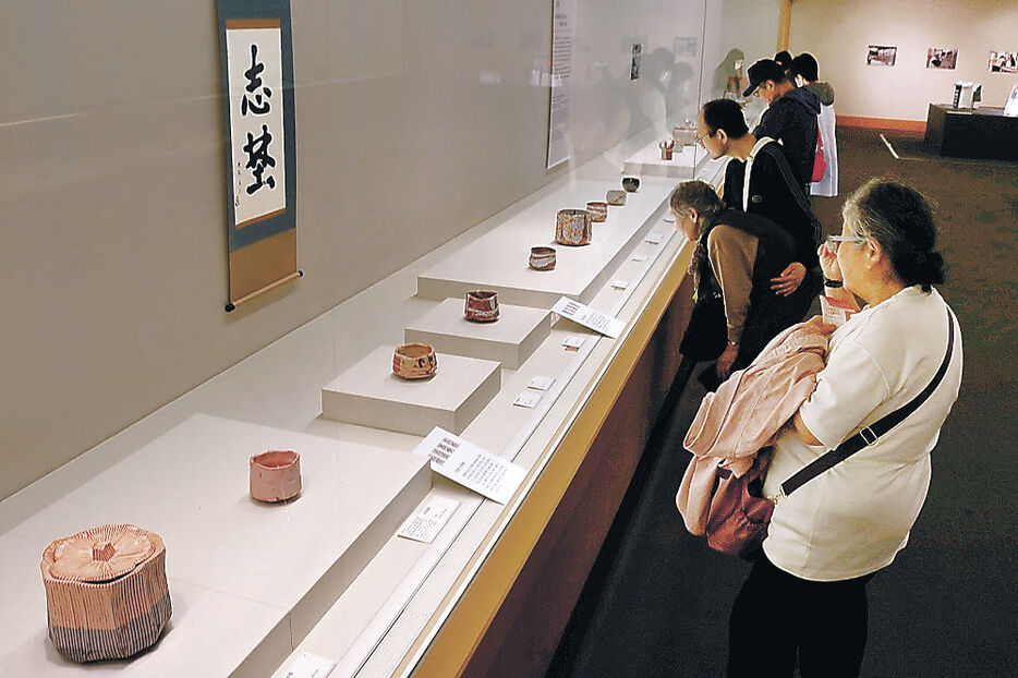 鈴木氏による茶碗や書に見入る来場者＝富山市の富山県水墨美術館