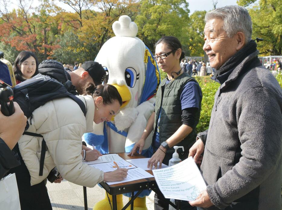 広島市の平和記念公園で署名する外国人観光客＝22日午後