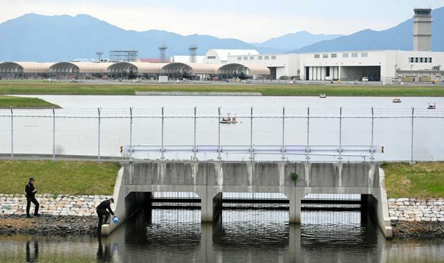 岩国基地北側遊水池の流出口で採水する市民団体メンバー=2024年10月31日午後2時3分、山口県岩国市三角町３丁目、鈴木史撮影