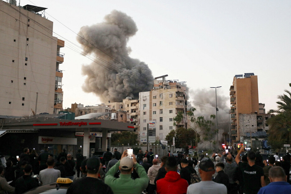 １４日、レバノンのベイルート南郊でイスラエル軍の空爆を受けて上がる煙を撮影する人々