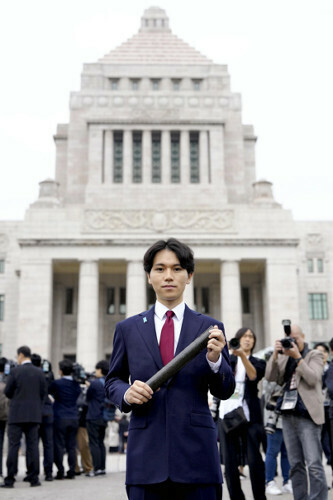 初登院し、国会を背に記念撮影する大空幸星氏（１１日午前９時２６分、国会で）＝若杉和希撮影