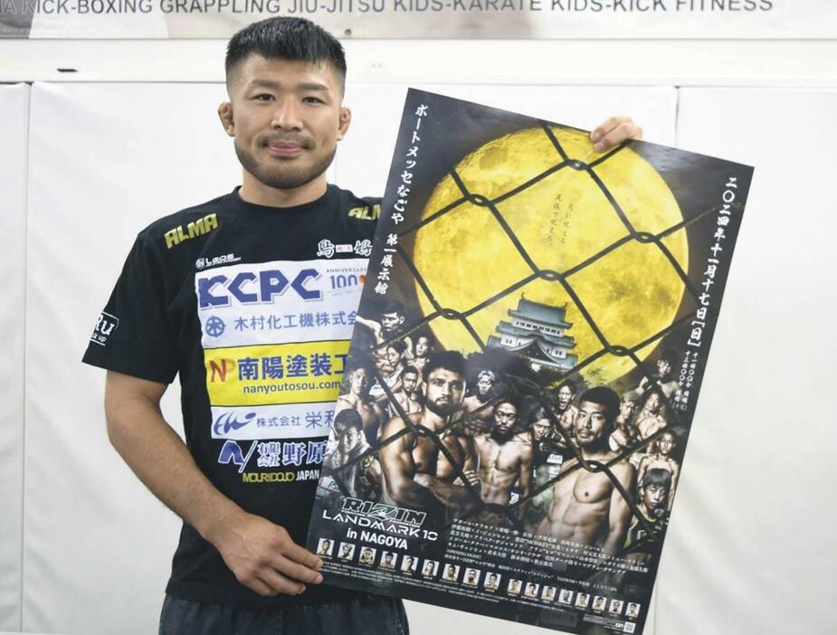 自身とケラモフ選手が一番大きくあしらわれた名古屋大会のポスターを手に「昔は隅で小さかった」と話す摩嶋一整選手＝周南市住吉町