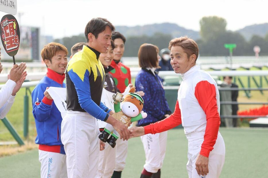 JRA通算500勝達成し、父親の岩田康誠騎手（右）と握手するの岩田望来騎手（撮影・安部光翁）