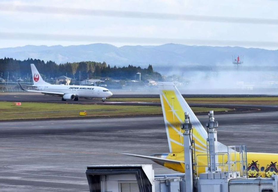 着陸後にタイヤがパンクし、白煙を上げた日航機＝３０日午後１時４５分ごろ、霧島市の鹿児島空港（冷水悠真さん提供）