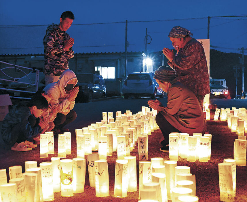 ろうそくに向かい手を合わせる住民＝１日午後５時１５分、輪島市町野町粟蔵