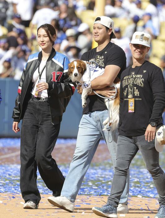 ドジャースタジアムで行われた優勝報告会を終え、愛犬デコピンを抱いて引き揚げる米大リーグ、ドジャースの大谷翔平。左は妻の真美子さん＝1日、ロサンゼルス（共同）