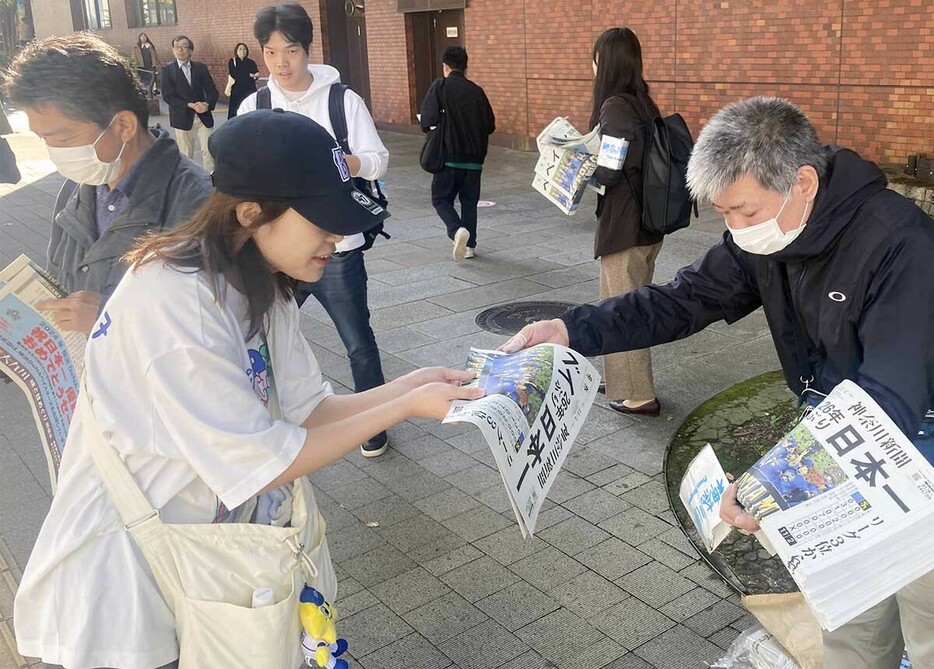 神奈川新聞の号外を受け取るベイスターズファンら＝４日午前１０時５分ごろ、ＪＲ関内駅前