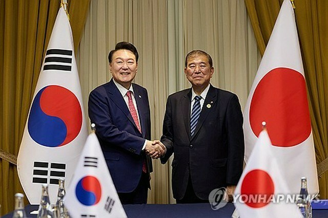 握手を交わす韓国の尹錫悦大統領（左）と日本の石破茂首相＝16日、リマ（聯合ニュース）