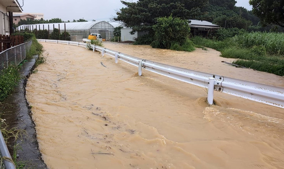 排水路（ガードレールから左）から水があふれ、右側の道路が冠水した＝8日午後2時半頃、与論町茶花（同町提供）