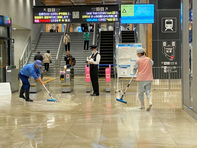 激しい雨で浸水したJR松山駅。掃除用具を使って水を懸命にかき出すメンテナンスの担当者ら=2024年11月2日午前11時58分、松山市南江戸1丁目、武田肇撮影