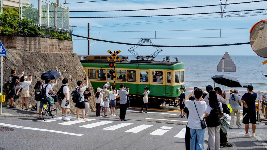 訪日客でにぎわう江の島電鉄・鎌倉高校前駅の踏切（時事）