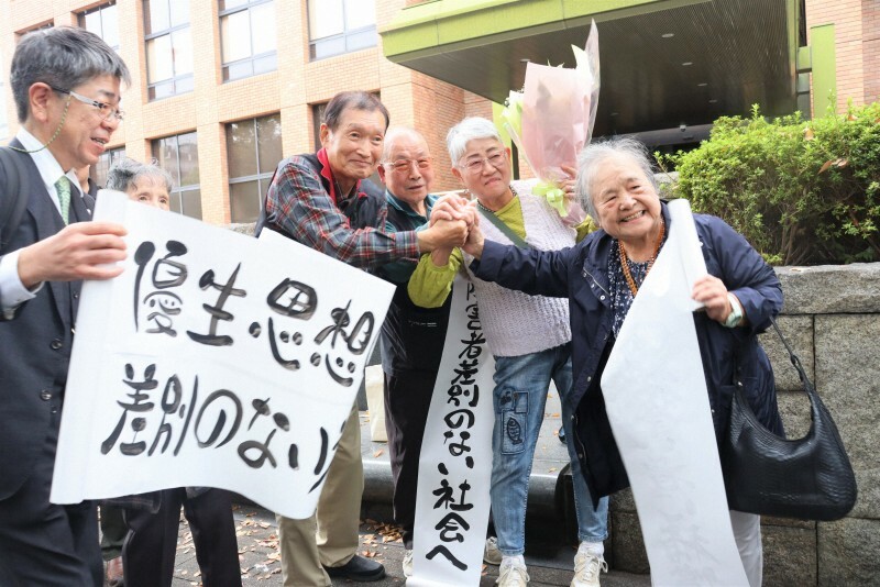 和解を喜ぶ尾上敬子さん（右から2人目）と夫一孝さん（同3人目）ら＝名古屋市中区の名古屋高裁前で2024年11月15日午後1時34分、塚本紘平撮影