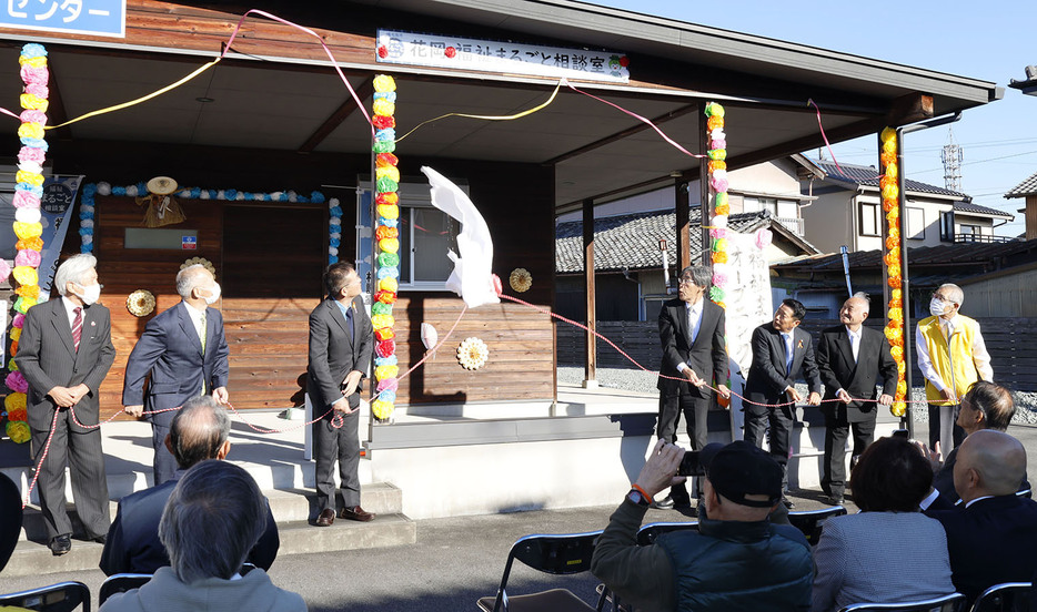 看板の除幕をした花岡地区での開設を祝う関係者ら＝駅部田町で