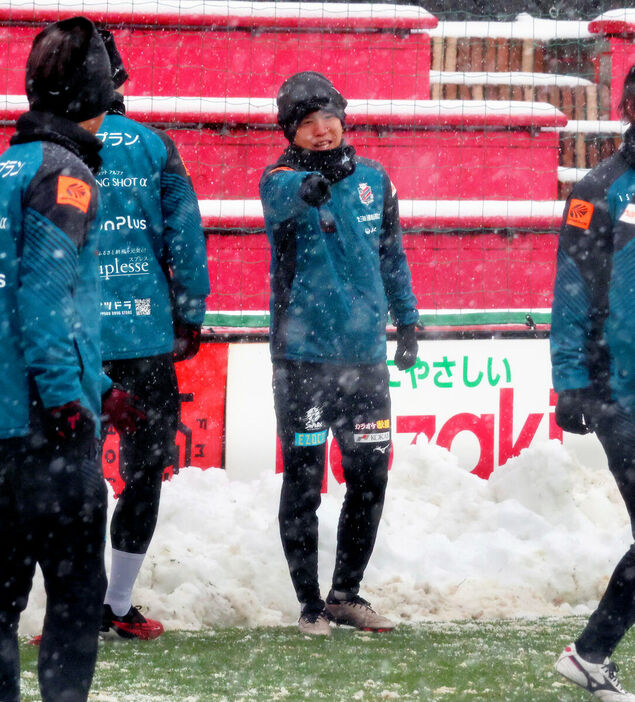 雪の中、仲間に笑顔で指摘する札幌ＭＦ浅野（中央）