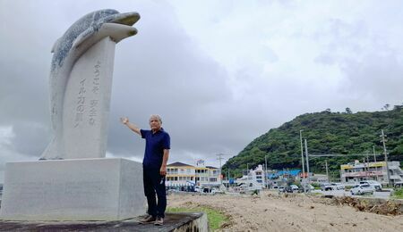 樹木が伐採され整地された交通安全の塔のイルカのモニュメントを紹介する世冨慶区の比嘉秀樹区長＝１０月２３日、名護市世冨慶の海岸