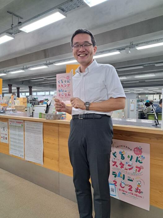 スタンプラリーの冊子を持つ同市産業振興課長の八谷俊太郎さん