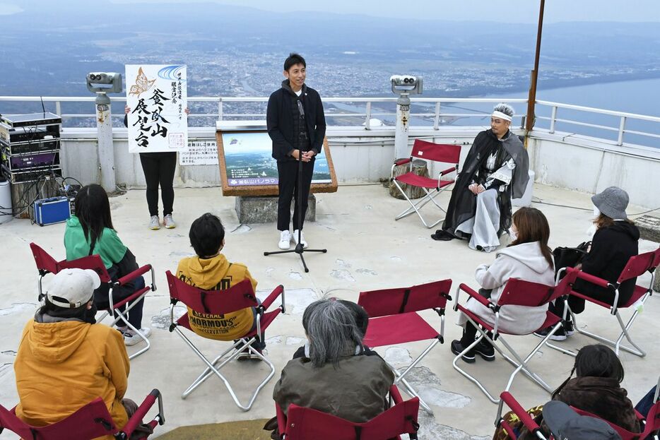 市街地を一望できる展望台屋上で「御光印」の説明をする山本市長（中）