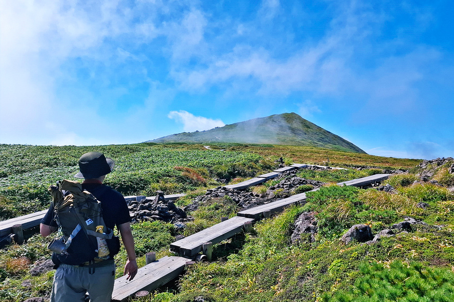 木道の登山道をトレッキングするハイカー