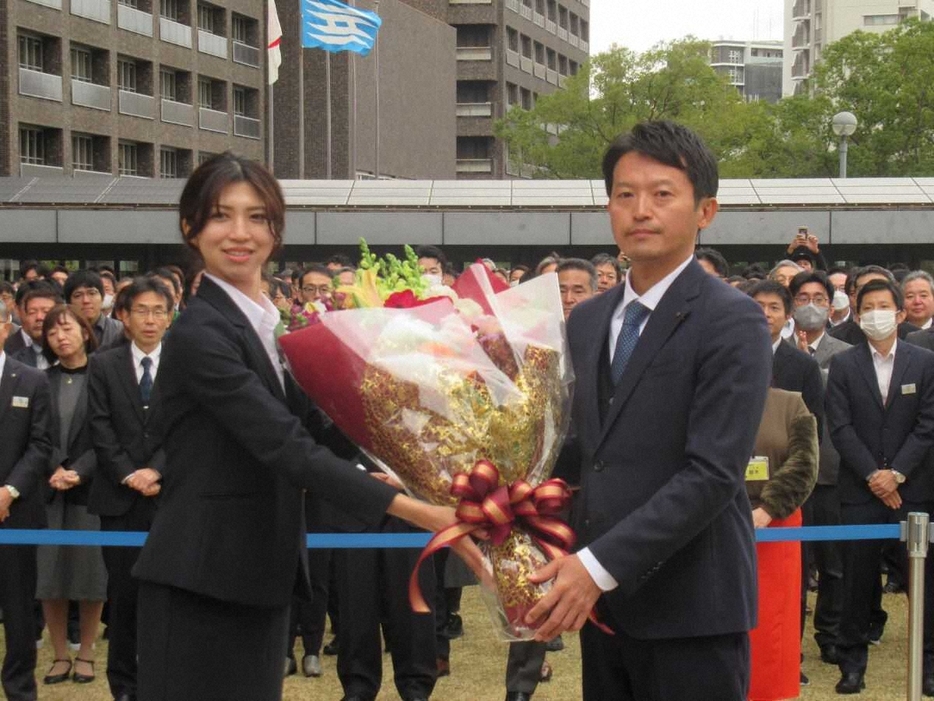 出直しの兵庫県知事選に当選し、‘’初‘’登庁した斎藤元彦知事（左）。職員から花束をもらう