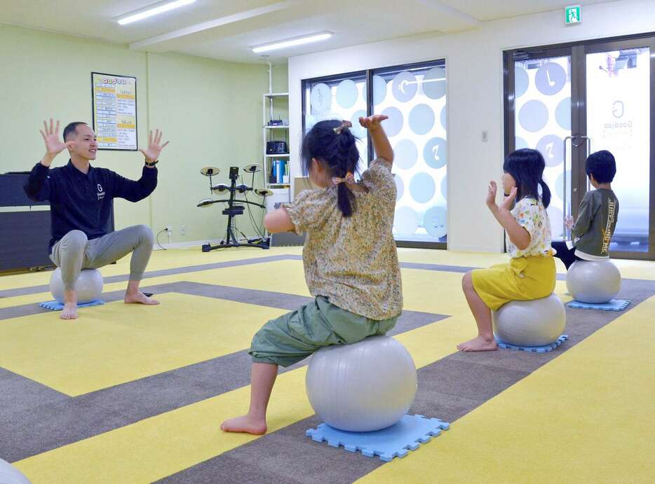 バランスボールに座り、音楽に合わせて体を動かす子どもたち＝５日、鹿児島市鴨池１丁目のグッジョブリズム