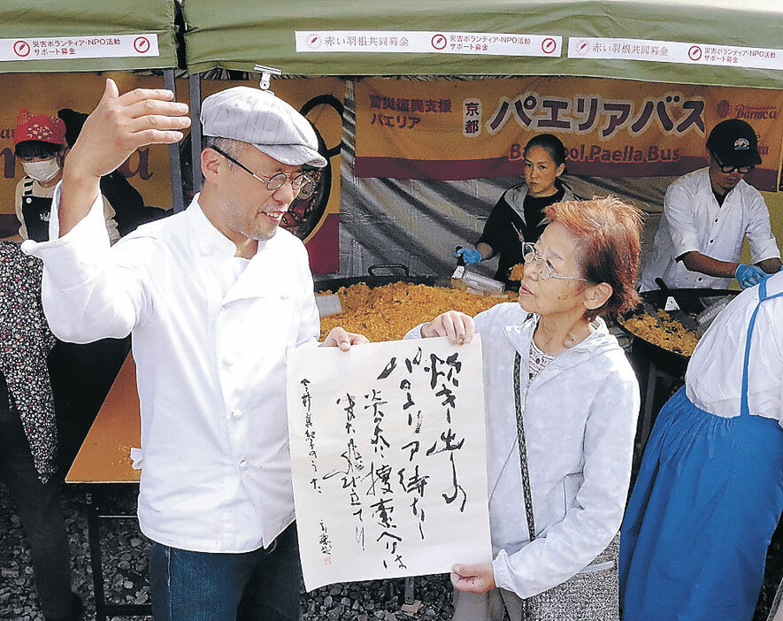 木下さん（左）から短歌の書を受け取る今井さん（右）＝輪島市の重蔵神社