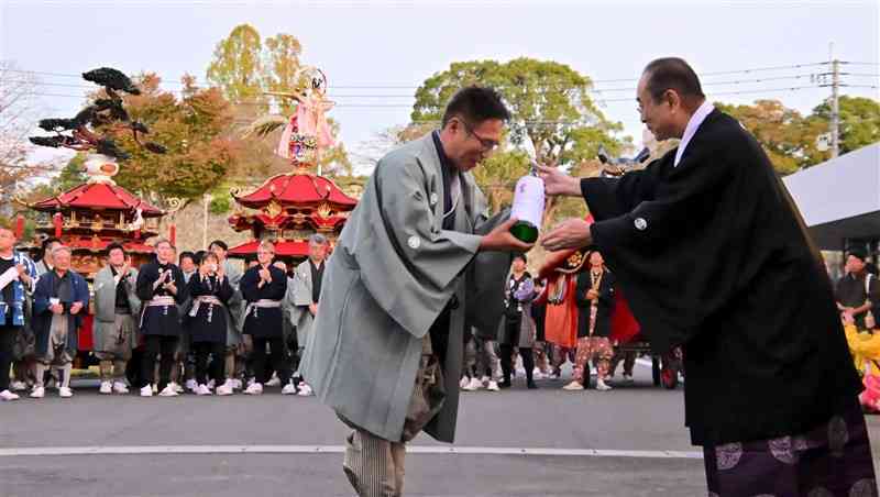 神幸行列の「納め式」で、奉納団体にお神酒を振る舞う松井葵之さん（右）＝23日、八代市（上島諒）