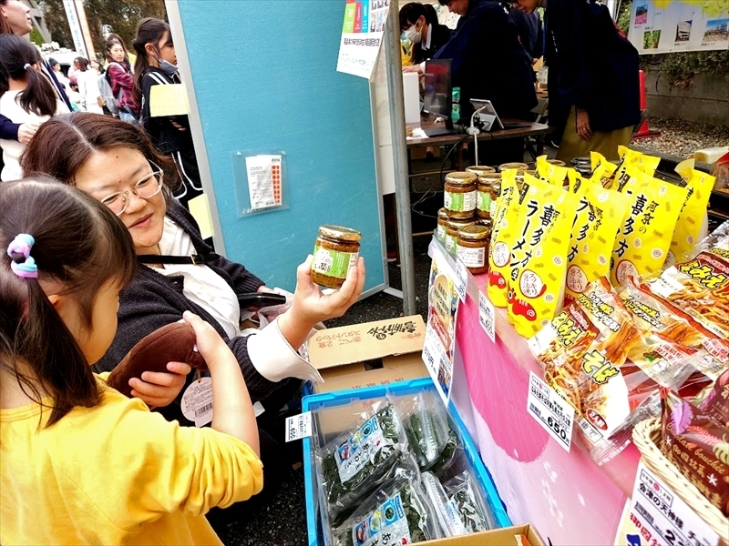 福島県産品のブースで「うまくてごめんな山菜」を手に取る来店者