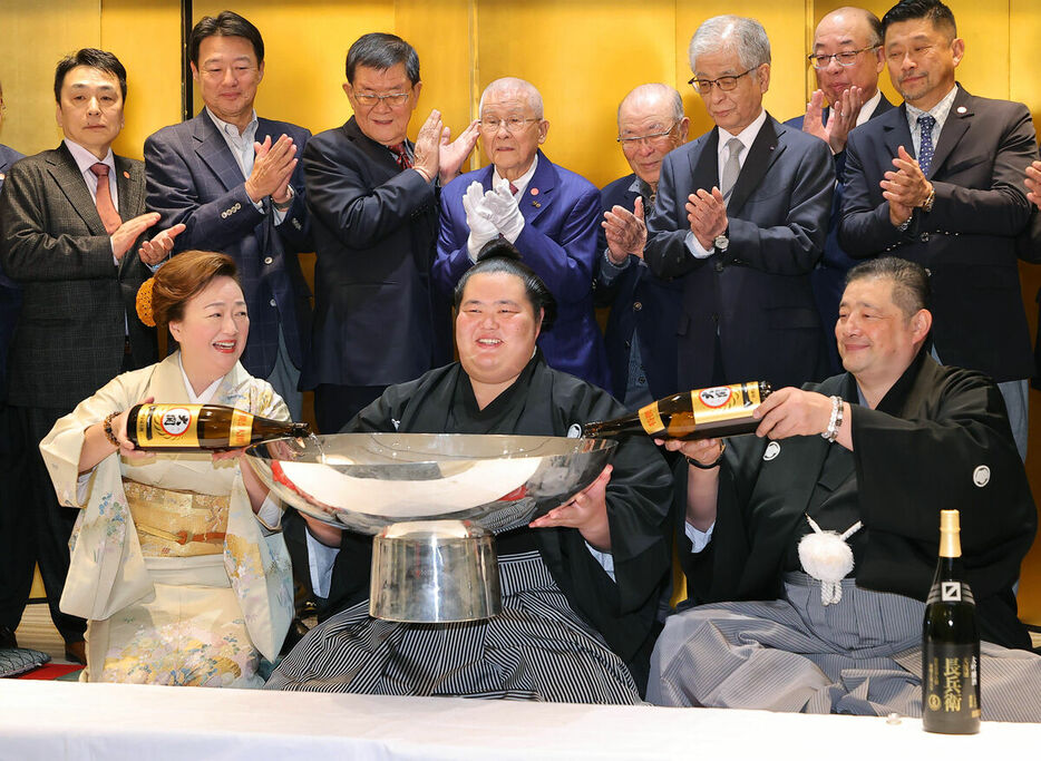 佐渡ケ嶽親方（右）、おかみの真千子さんから銀杯に酒を注がれ、笑顔を見せる琴桜（カメラ・豊田　秀一）