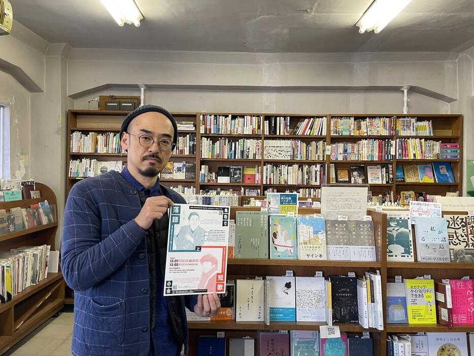 「鳥取で短歌と落語の会」のチラシを持つ、店主の高木善祥さん