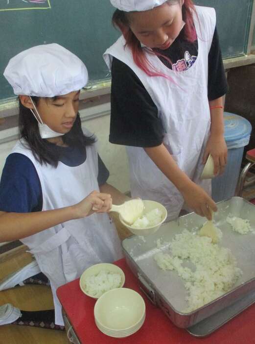 給食の時間となり、但馬村岡米を盛る児童ら＝大阪府門真市立上野口小学校（格清政典撮影）