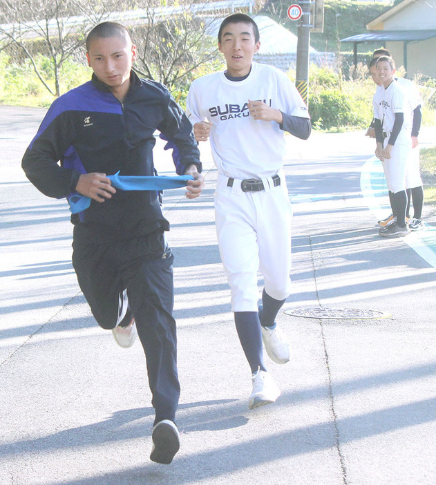 駅伝本番に向けての練習で、森野選手（手前から2人目）からたすきを受けて走る伊藤豊選手＝大台町茂原の昴学園高で