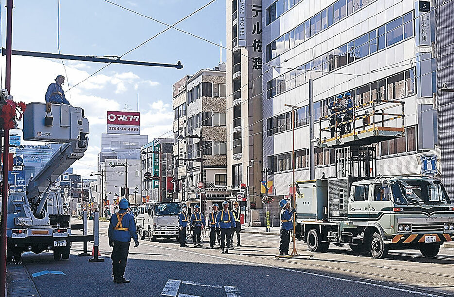 市内電車の架線が切断し、復旧工事を急ぐ作業員＝２５日正午、富山市新富町