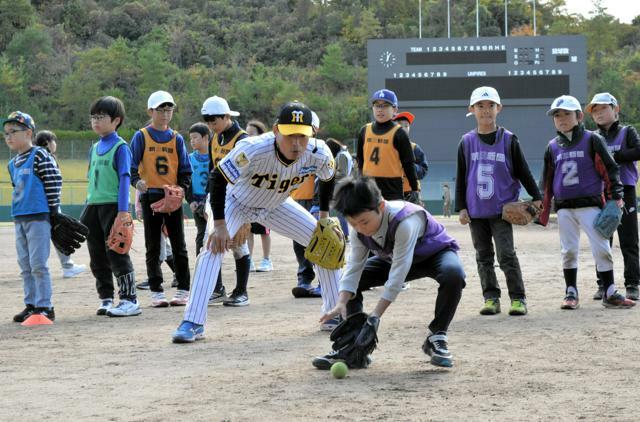 子どもたちにゴロの捕球と送球を指導するユニホーム姿の桧山進次郎さん=2024年11月24日、松江市上乃木10丁目の市営野球場、石川和彦撮影