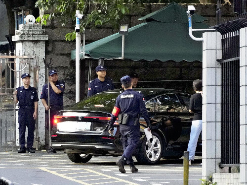 中国広東省の深圳日本人学校で通学のための車両が入る中、警戒する治安要員ら（１０月１７日）