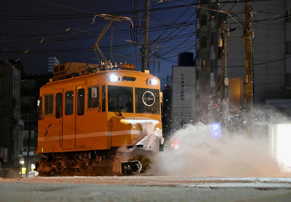 今季初めて出動し、路面電車の軌道に積もった雪を掃き飛ばす「ササラ電車」＝19日午前5時49分、札幌市