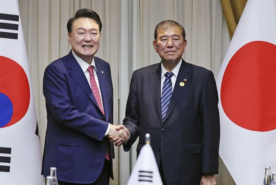 会談を前に握手する石破首相（右）と韓国の尹錫悦大統領＝16日、ペルー・リマ（代表撮影・共同）