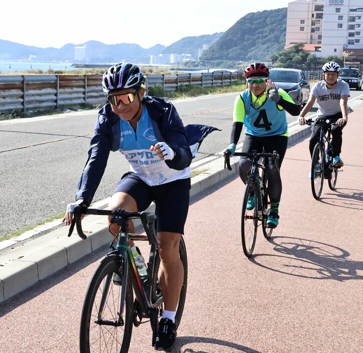 前園さん(手前)と大毛海岸沿いを自転車で走るイベントの参加者ら＝鳴門市鳴門町土佐泊浦大毛