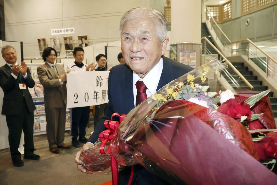 退任で贈られた花束を手に笑顔で青森県田舎館村役場を後にする、現職首長で全国最高齢の鈴木孝雄村長＝15日午後