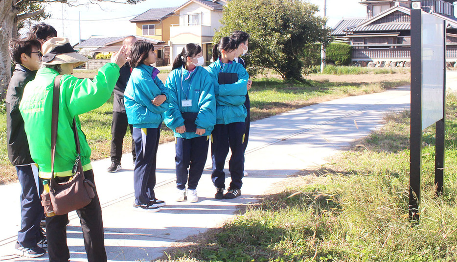 斎宮跡を歩き、史跡について案内を受ける明和中学生たち＝明和町斎宮で