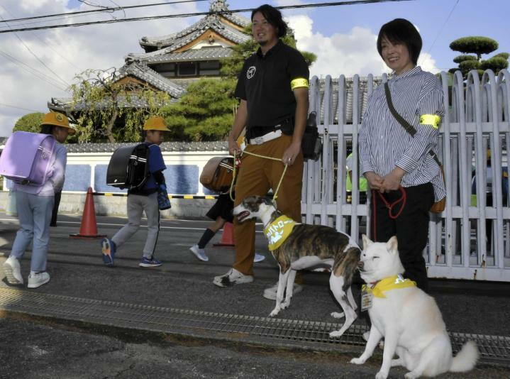 下校する児童を見守る「わんパト隊」の犬と飼い主＝5日午後、松山市越智1丁目