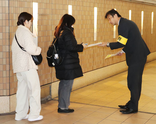 【情報提供を求めるちらしを受け取る駅利用者ら（左）＝松阪市嬉野中川新町の近鉄伊勢中川駅で】