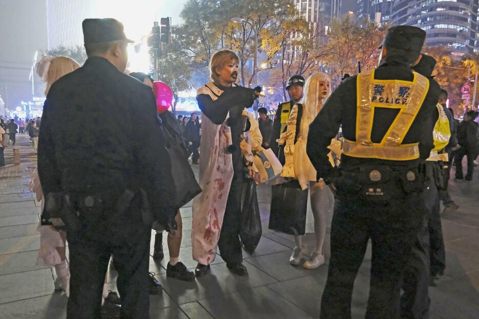 ハロウィーン期間中、北京市内の繁華街で警察官らに取り囲まれるコスプレした若者＝10月（共同）