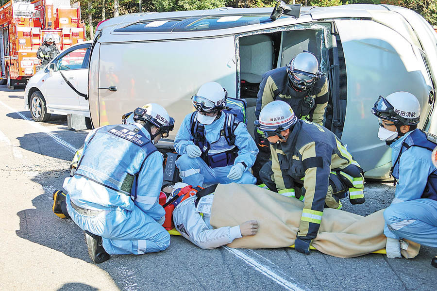 横転した車両からけが人を救助する消防隊員