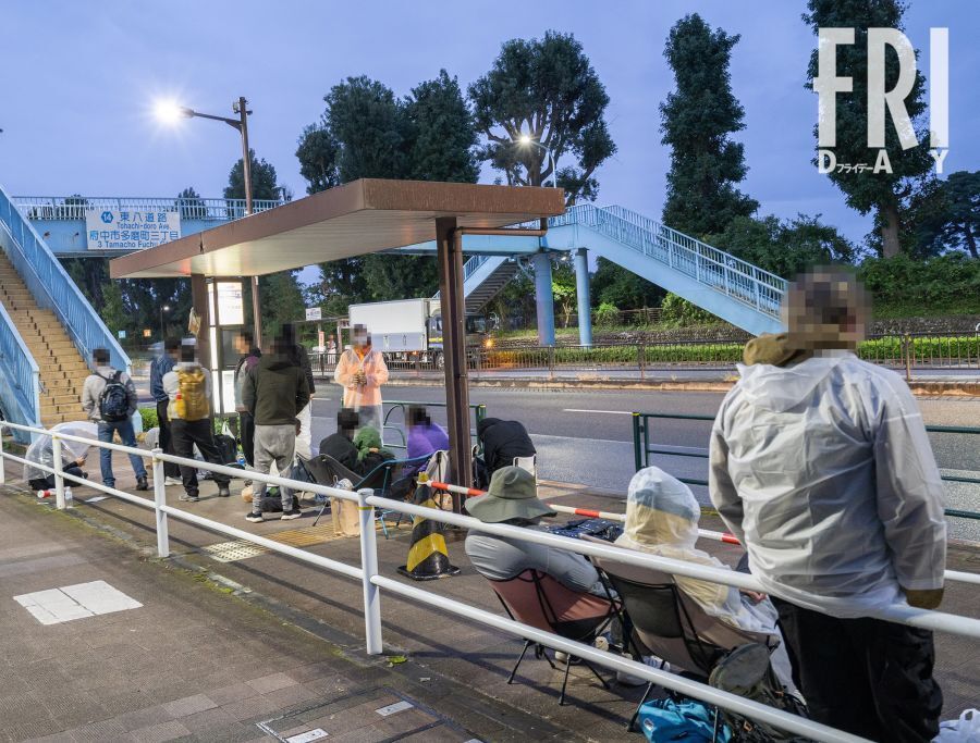 府中試験場で開門を待つ外国人と思われる人々。霧雨から逃れるようにバス停に身を寄せ合っていた