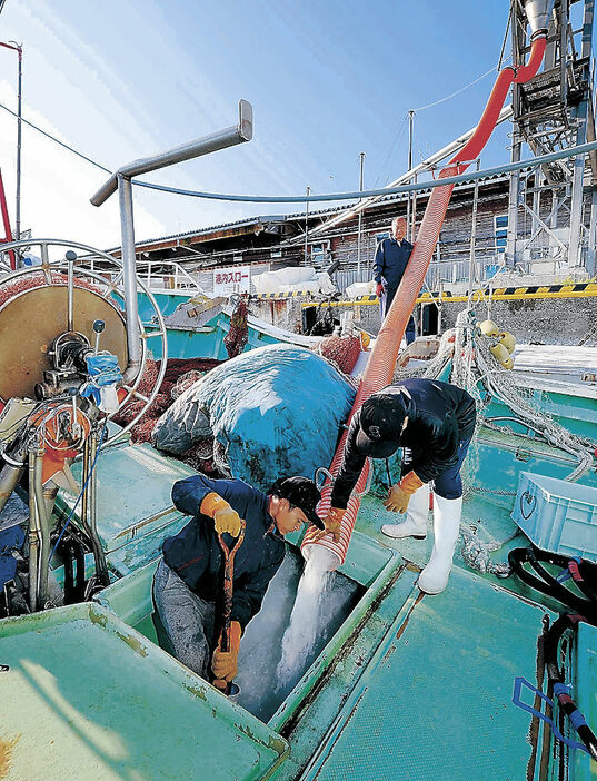 カニ漁に向け、漁船に氷を積み込む漁師＝輪島港