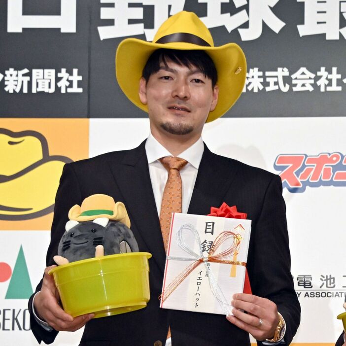 プロ野球最優秀バッテリー賞を受賞し、イエローハットをかぶり記念品を手にする有原（撮影・冨永豊）