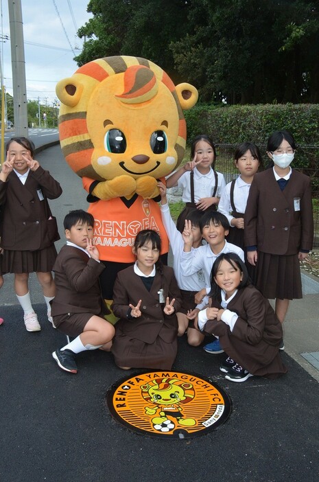 かわいいマンホールのふたに大喜びの児童とレノ丸（市立サッカー交流公園入り口で）