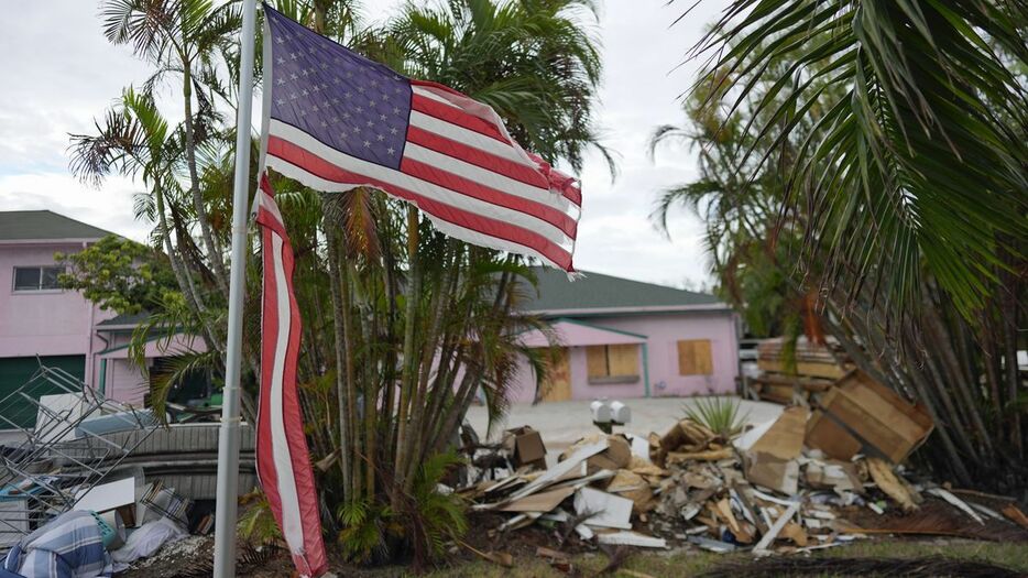 米南部を襲ったハリケーンで裂けた庭先の星条旗＝10月8日、フロリダ州アンナマリア島（AP）