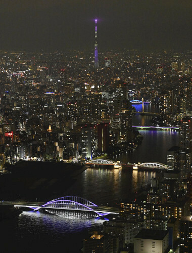 紫色にライトアップされた隅田川に架かる橋（手前は築地大橋、奥は東京スカイツリー）（１２日、東京都内で、読売ヘリから）＝大石健登撮影